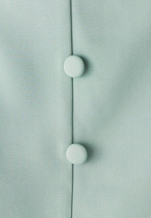 Heleheimne rohelise värvi kangas, millel on sile tekstuur ja millel on vertikaalsel õmblusel kaks kangaga kaetud nööpi.