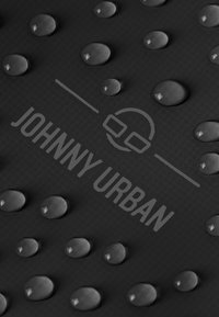 Fekete textúrájú felület vízcseppekkel és a "JOHNNY URBAN" felirattal, amelyhez egy kör alakú logó is tartozik, mindez egy letisztult dizájnban van megjelenítve.