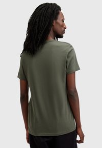 T-shirt in cotone verde oliva con maniche corte e colletto rotondo, texture liscia e vestibilità rilassata, vista da dietro.