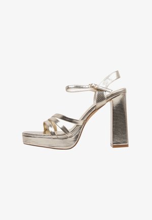 Sandales à talons hauts argentées métalliques avec un talon épais, bout ouvert et plusieurs sangles à l'avant. Comprend une bride à boucle autour de la cheville et une finition texturée.