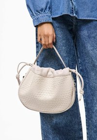 Beige punottu nahkainen käsilaukku, jossa on kerätty yläosa ja kaksinkertaiset kahvat. Pinnassa on kuvioitu rakenne ja pehmeä pinta.