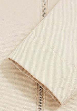 Beige textured fabric sleeve with a visible zipper, showcasing a ribbed pattern and clean stitching. Smooth finish with a slight sheen.