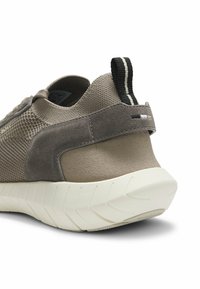 Talons de baskets en tricot beige et gris avec surpiqûres en daim, languette rayée noire et blanche, et semelle blanche épaisse texturée sur fond blanc.