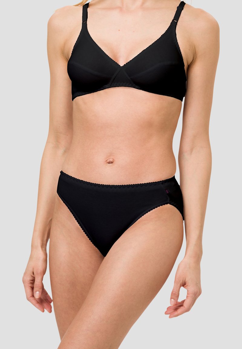 Schwarzer BH aus Netzstoff, ungepolsterte Schalen und verstellbare Träger. Passende schwarze High-Waist-Slips mit gewelltem Rand.
