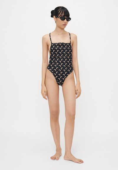 Costum de baie dintr-o singură piesă, negru, cu un model geometric de lună în crescende, bej. Prezintă bretele subțiri și ajustabile, și un design cu picioare înalte.