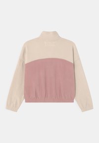 Fleecejack met een hoge kraag, een beige bovenstuk en een roze onderstuk met elastische tailleband en manchetten. Zachte textuur.