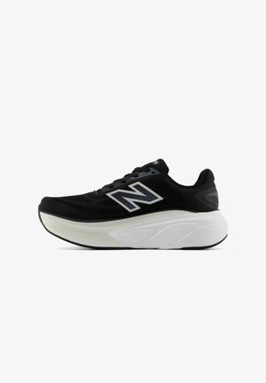 Chaussure de sport noire avec une tige texturée, portant un logo "N" argenté bien visible, une semelle blanche rembourrée et un design à lacets.