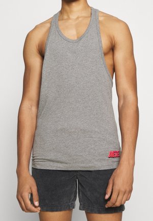 Débardeur gris en coton, doté d'un dos nageur. Logo rouge sur le côté inférieur. Porté avec un short sombre texturé.