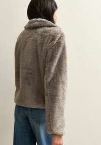 Gray faux fur jacket with a wide collar, long sleeves, and a soft texture, paired with blue denim jeans. Back view shows relaxed fit.