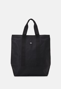 Black tote bag made of durable fabric, featuring two fabric handles, a rectangular shape, and a small logo tag on the front.
