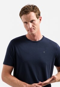 Marineblauwe t-shirt met korte mouwen van zacht katoen. Heeft een minimalistisch logo op de borst, een ronde hals en een gladde textuur.