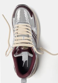 Srebrne siatkowe buty sportowe z burgundowymi akcentami, z wyściełanym kołnierzem, kremowymi sznurówkami i teksturowaną gumową podeszwą.