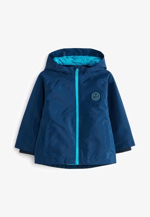 Veste à capuche bleu marine pour enfants avec une fermeture éclair turquoise vif, motif géométrique à l'intérieur de la capuche et un patch visage souriant qui fait un clin d'œil sur la poitrine.