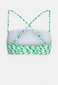 Bralette verde e branco com padrão, com alças em cruz nas costas, apresentando uma textura suave e um design esportivo e estruturado.
