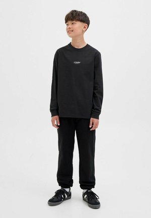 Schwarzes Langarm-Sweatshirt mit Logo auf der Brust, kombiniert mit schwarzen Jogginghosen und schwarzen Turnschuhen. Entworfen für Komfort und Freizeitgestaltung.
