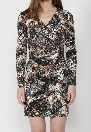 Mujer con un vestido de manga larga y escote en V con un estampado de leopardo marrón y negro y paisley.