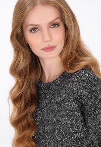 Grijze gebreide trui met een textuur, voorzien van een ronde halslijn en lange mouwen, tegen een witte achtergrond.