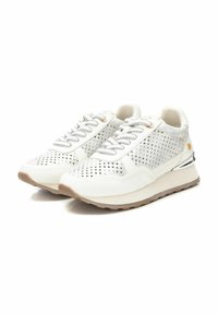 Zapatillas deportivas blancas con parte superior perforada, cordones grises y suela color marrón claro. Presentan detalles metálicos ligeros y un diseño redondeado.