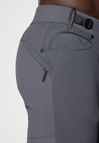 Graue Wanderhosen mit einem schlanken Design, elastischem Bund mit Gürtel, einer Reißverschlusstasche und glatter Stoffstruktur.