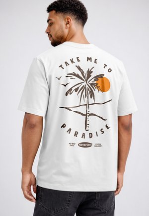 Man wearing white t-shirt with palm tree, sun, and birds graphic and text "Take me to paradise" on the back.