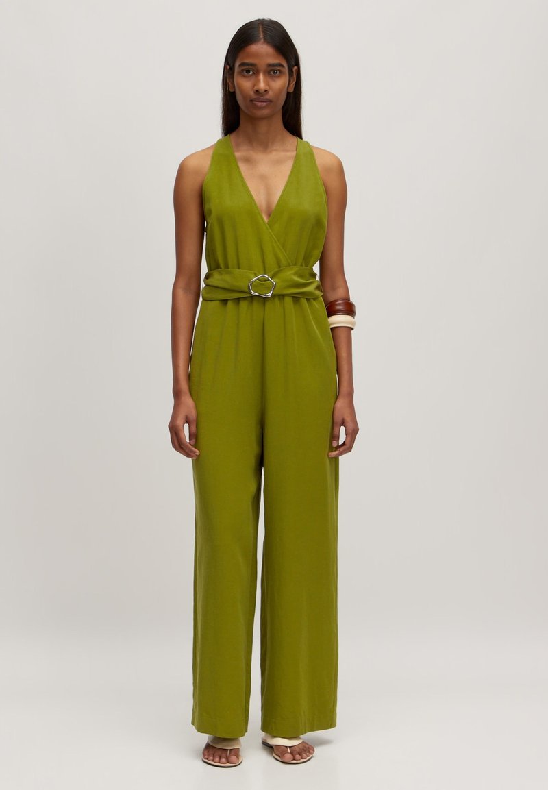 Grüner Jumpsuit mit tiefem V-Ausschnitt, weit geschnittenen Hosenbeinen und einem Stoffgürtel mit einer runden Schnalle. Glatte Textur und lockere Passform.