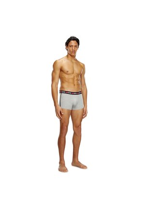 Graue Boxer-Briefs mit einem schwarz-roten elastischen Bund, auf dem das „Diesel“-Logo zu sehen ist, präsentiert an einem männlichen Model vor einem neutralen Hintergrund.