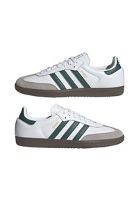 Vita lädersneakers med gröna ränder och detaljer, mockatåhuvud och brun gummisula. Har "Samba"-logotyp i guld.