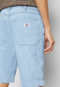 Světle modré džínové cargo šortky mají několik kapes, tkanou značkovou etiketu na zadní straně a rovný střih s klasickým designem.