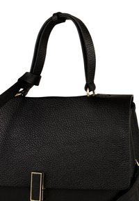 Zwarte leren handtas met een gestructureerde afwerking, voorzien van een gouden schuifsluiting en verstelbare riem, met een strak ontwerp.