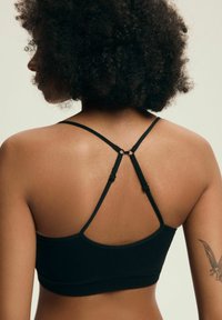 Czarny sportowy stanik z regulowanymi ramiączkami, z krzyżowym wzorem na plecach i gładką fakturą. Bez widocznych wzorów ani elementów metalowych.