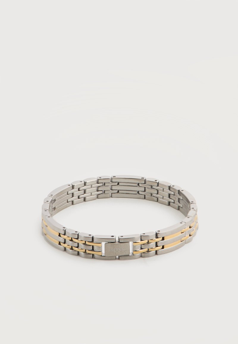 Βραχιόλι αλυσίδα από μέταλλο σε ασημί και χρυσούς τόνους με ορθογώνιο κούμπωμα χαραγμένο με το όνομα μάρκας σε λευκό φόντο.