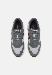 A Levi's szürke és burgundi sportcipők hálós és velúr felsőrészük, párnázott nyelvük, fűzőik és bordázott gumitalpuk jellemzik.