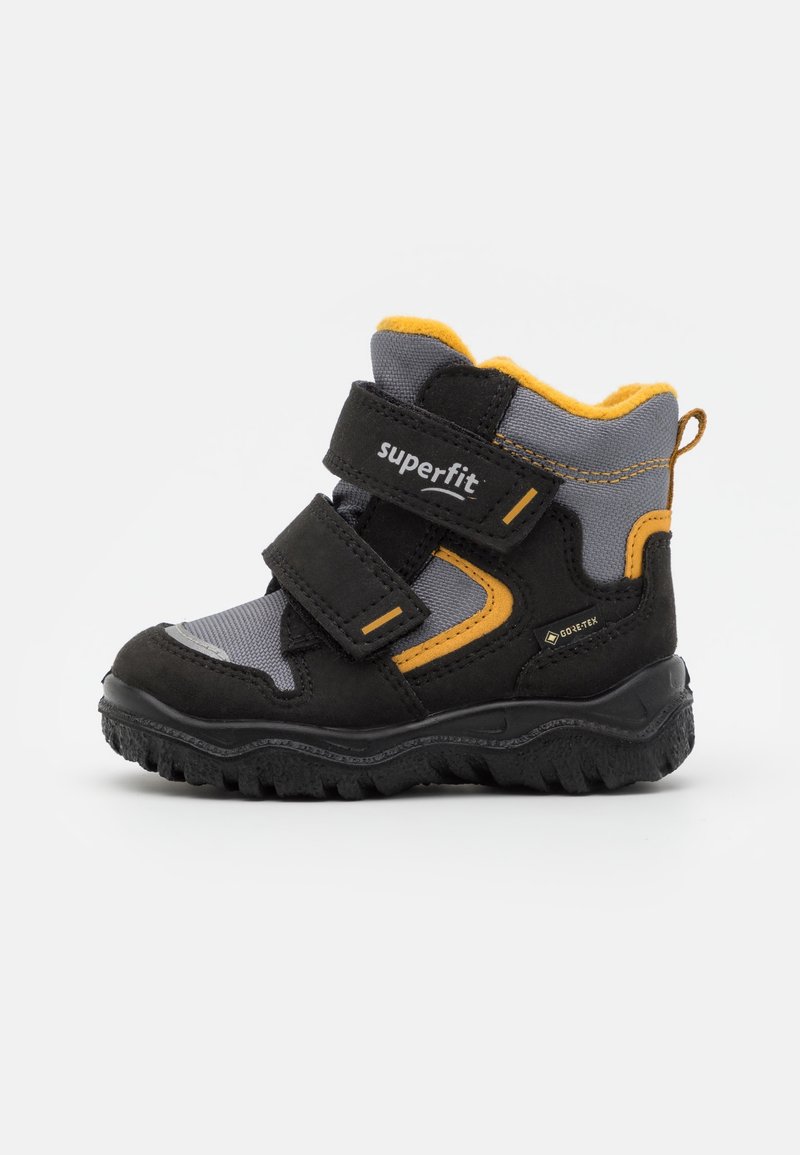 Botte de randonnée pour enfant en noir et gris avec accents jaunes, deux bandes velcro et semelle robuste, conçue pour une utilisation en extérieur avec matériau Gore-Tex.