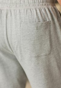 Graue Jogginghosen mit weicher Textur, ausgestattet mit einem elastischen Bund und einer einzelnen Gesäßtasche. Einfaches Design, geeignet für Freizeitmode.