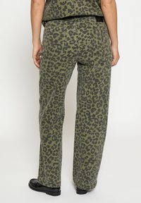 Nohavice s leopardím vzorom v olivovo zelenej farbe, so zľahka voľným strihom, rovnými nohavicami, dvoma zadnými vreckami a čiernymi detailmi na páse.