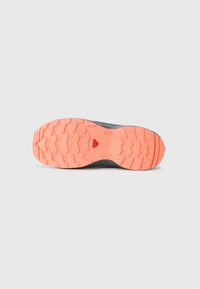 Shoe outsole featuring a textured tread pattern in orange with black accents. Sturdy rubber material designed for traction.