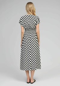 Robe midi à rayures noires et blanches avec des manches courtes, taille élastique et ballerines noires unies. Tissu lisse avec un motif diagonal.