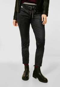 Svarta, slim-fit byxor i ett mjukt, mockaliknande material med dragsko i midjan, med kontrasterande sömmar och en slät yta.