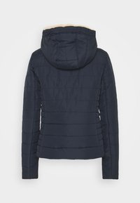 Marinblå puffjacka med huva, med horisontella quiltade linjer och ett mjukt foder runt halsen. Långa ärmar och smal passform.