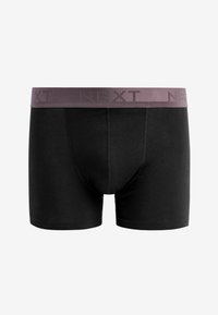 Schwarze Boxershorts mit einem helllila elastischen Bündchen, das das Wort "NEXT" in einem wiederholten Muster zeigt. Glatte Textur und figurnahe Form.