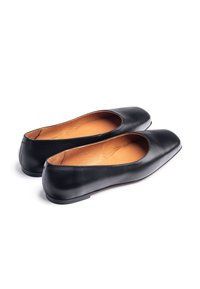 Ballerines en cuir noir avec intérieur marron, bout arrondi, talon bas et texture lisse. Aucun élément métallique ni motif visible.