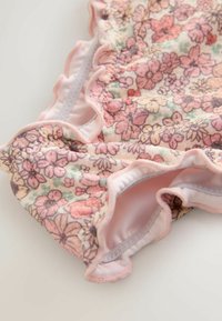 Cvetlično kopalno oblačilo v pastelno roza barvi z nabranimi robovi in mehko teksturo. Ponaša se s cvetličnim vzorcem v odtenkih roza, zelene in sivordeče.