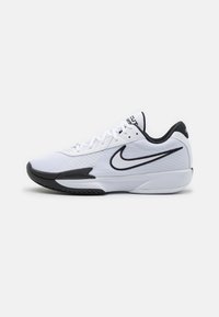 Baskets blanches avec une tige en mesh texturé, accents noirs, logo emblématique de Nike, et semelle en caoutchouc noire.