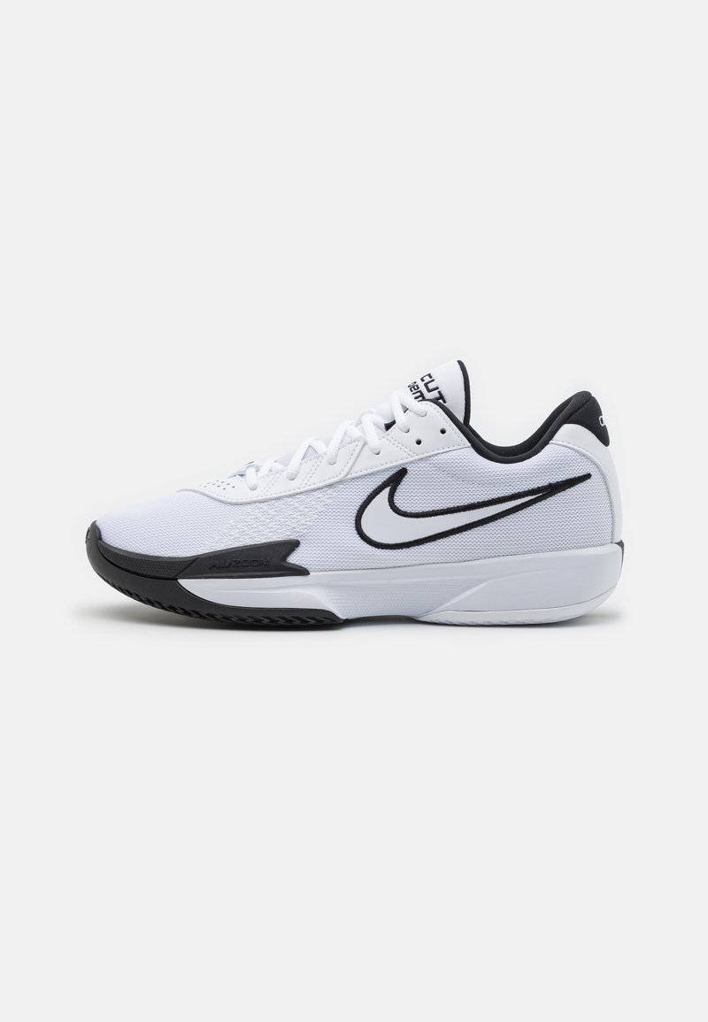 Baskets blanches avec une tige en mesh texturé, accents noirs, logo emblématique de Nike, et semelle en caoutchouc noire.