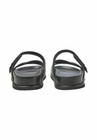 Schwarze Leder-Sandalen haben eine flache Sohle und zwei Kreuzriemen. Das Design ist minimalistisch, ohne sichtbare Muster oder Beschläge.