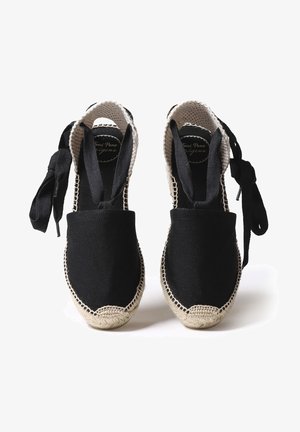 Espadrilles en toile noire avec semelles en jute naturel, dotées de larges liens en tissu et d'un détail de bord tressé à la base.