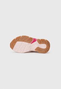 Suola di una sneaker Fila in gomma rosa chiaro e marrone con modelli di battistrada e un piccolo logo Fila rosso vicino al centro.