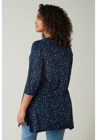 Schwarze Bluse mit lila und grünem Blumenmuster, 3/4-Ärmel, abgerundeter Saum und leichtem Stoff. Mit geknöpftem Rücken.