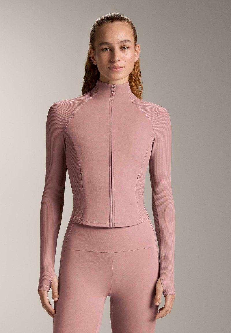 Dusty rose zip-up jacket with ribbed texture, long sleeves, and fitted design. Paired with matching high-waisted pants.
