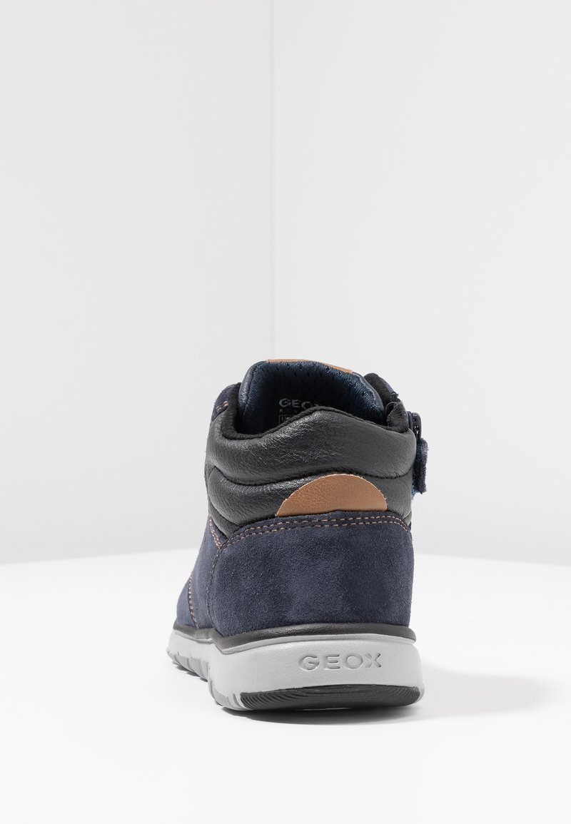 Granatowe zamszowe i skórzane botki za kostkę z szarym spodem, z brązowym okrągłym akcentem i detalami haftu, zaprojektowane z myślą o wygodzie i oddychalności.